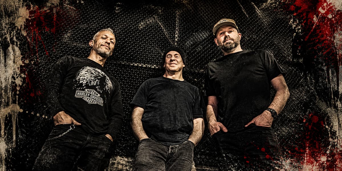 Demons and Disciples band members posing against an industrial backdrop with a gritty punk rock aesthetic and dark red grunge accents.