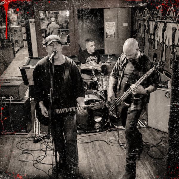 Demons and Disciples playing a live set at a local venue featuring vocals, bass, and drums.